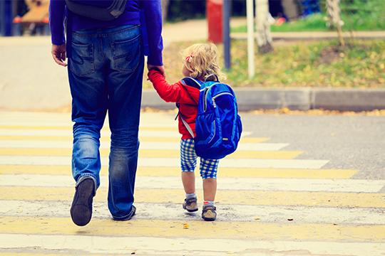 Man holding a toddler crossing the street