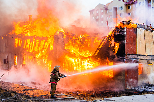 Fireman hosing off a burning property