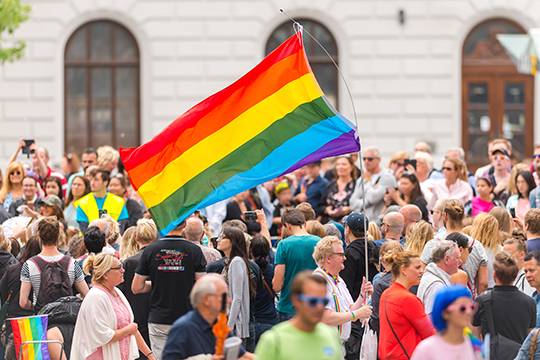 Man with a big rainbow flag in a street crowd