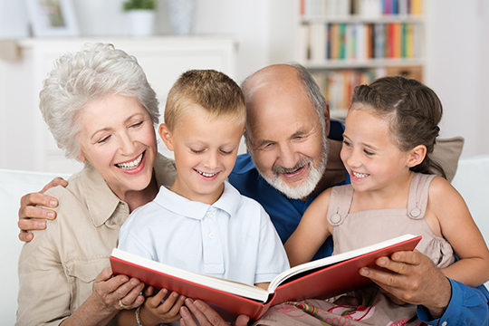 Grandparents happily reading a book with their grandchildren