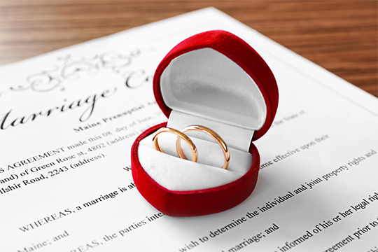 Wedding rings in a box over a marriage contract