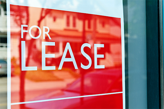 Red and white For Lease sign in a glass window